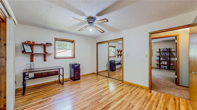 bedroom featuring light wood-style floors, multiple windows, baseboards, a closet, and a textured ceiling