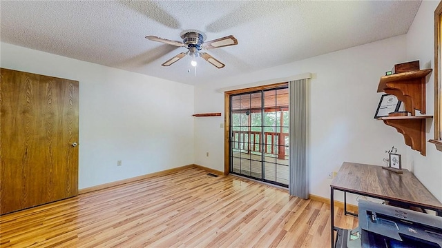 interior space featuring light wood-style floors, ceiling fan, a textured ceiling, and baseboards
