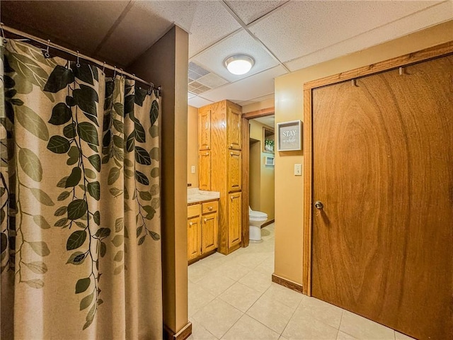 full bathroom with toilet, tile patterned floors, a drop ceiling, vanity, and a shower with curtain