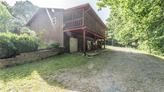 rear view of property with a sunroom, driveway, a wooden deck, and a yard
