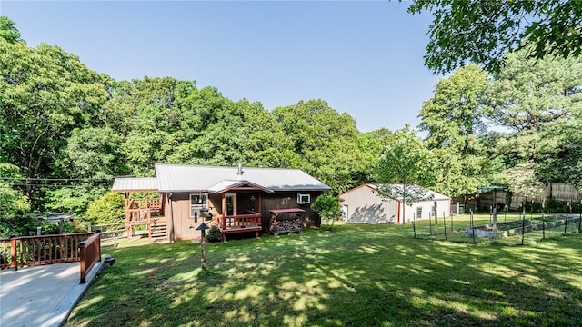 back of house with a vegetable garden, a deck, and a forest view