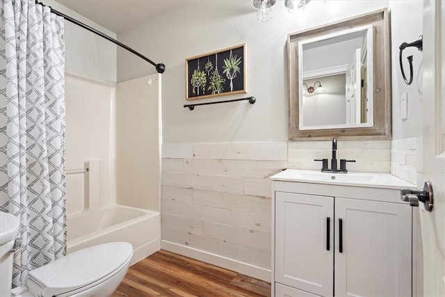 bathroom with toilet, wood finished floors, shower / bathtub combination with curtain, vanity, and a wainscoted wall