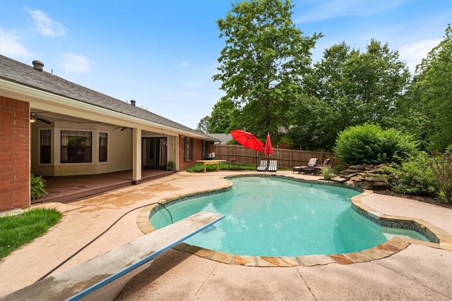 view of pool featuring a wooden deck, fence, a ceiling fan, and a patio