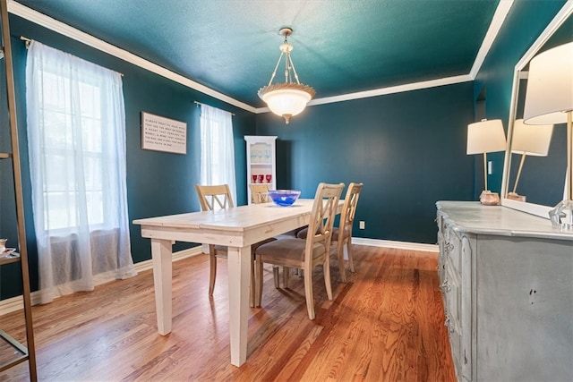 dining space featuring light wood-style flooring, ornamental molding, and baseboards