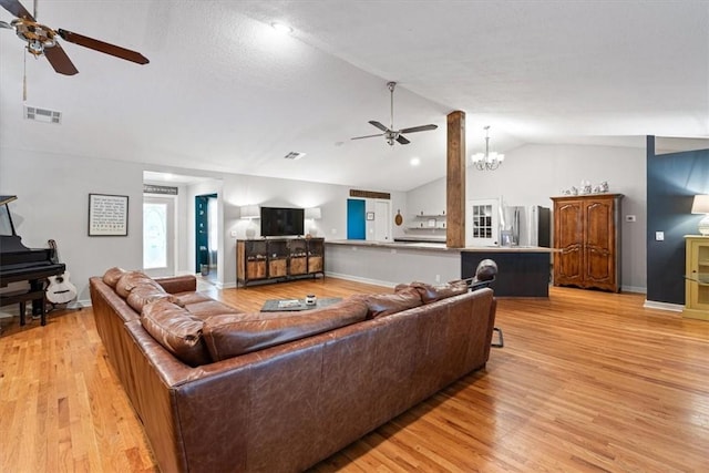 living room with a ceiling fan, lofted ceiling, light wood-style flooring, baseboards, and a chandelier