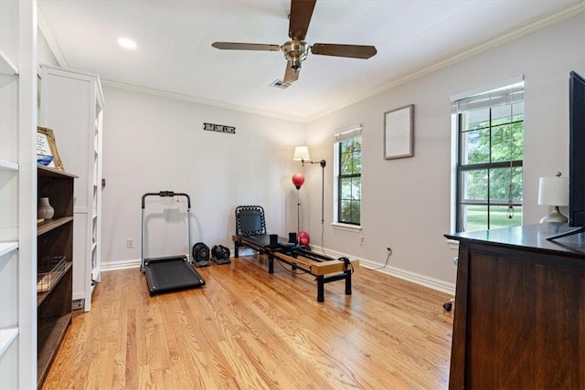 workout area with light wood-style flooring, healthy amount of natural light, a ceiling fan, crown molding, and baseboards