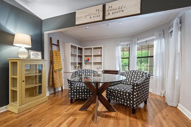 dining area with light wood-style floors, crown molding, and baseboards