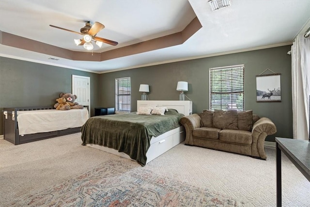 carpeted bedroom featuring a raised ceiling, ornamental molding, and ceiling fan