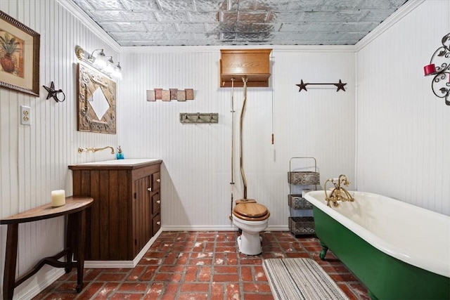 full bath featuring a freestanding tub, vanity, ornamental molding, toilet, and an ornate ceiling