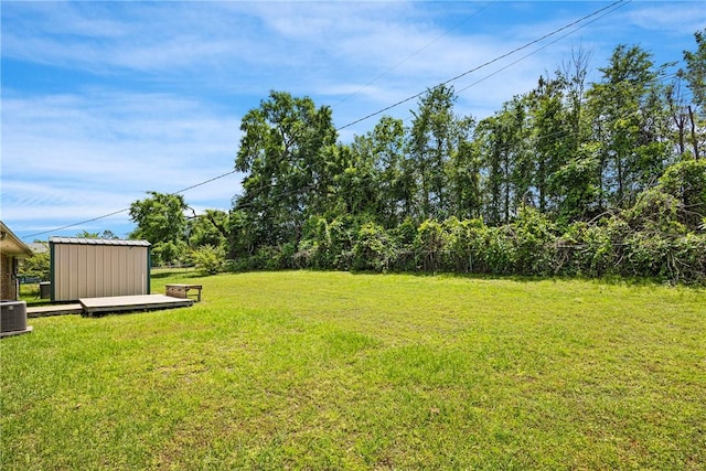 208 Date St, Russellville, AR 72802 - view of green lawn featuring an outdoor structure, a wooden deck, central AC, and a storage shed