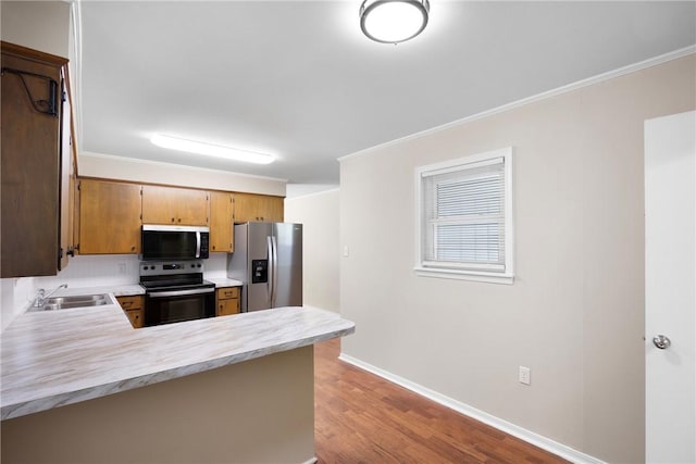 208 Date St, Russellville, AR 72802 - kitchen featuring stainless steel appliances, a sink, light countertops, a peninsula, and wood finished floors