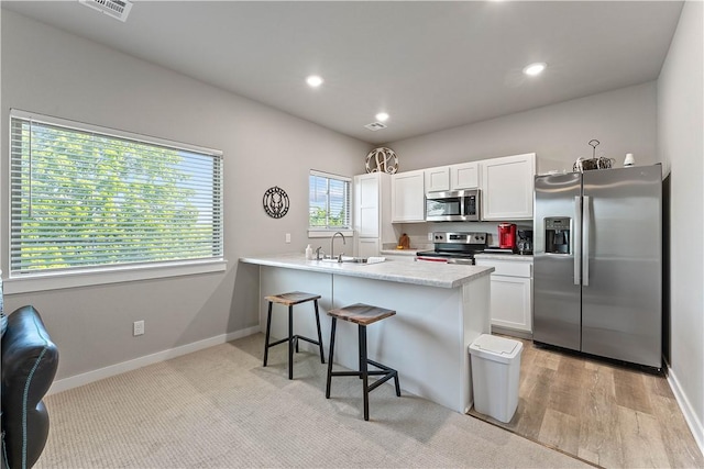 293 W Ash St Unit 1, Fayetteville, AR 72703 - kitchen featuring stainless steel appliances, white cabinetry, a breakfast bar, a sink, and a peninsula