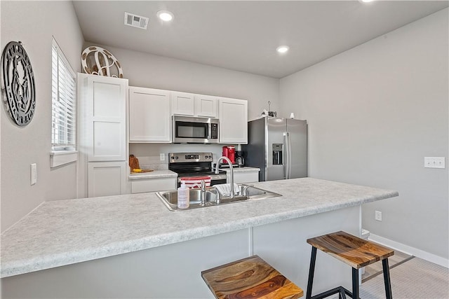 293 W Ash St Unit 1, Fayetteville, AR 72703 - kitchen featuring appliances with stainless steel finishes, a sink, a kitchen bar, white cabinetry, and recessed lighting