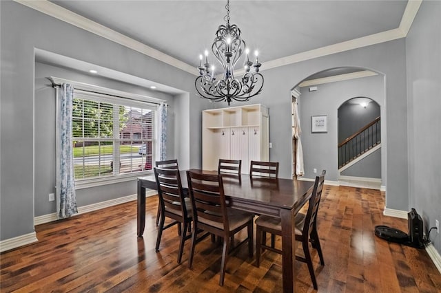 dining space featuring wood finished floors, arched walkways, baseboards, a chandelier, and ornamental molding