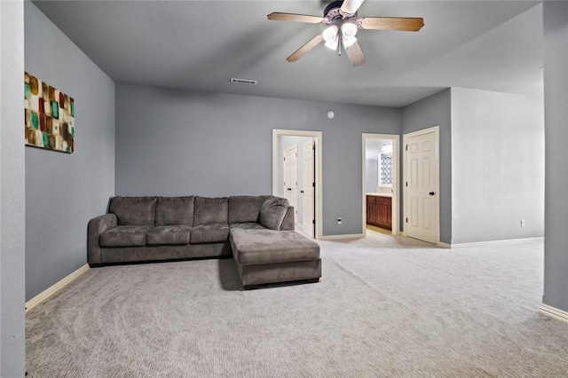 living area with baseboards, light carpet, and a ceiling fan