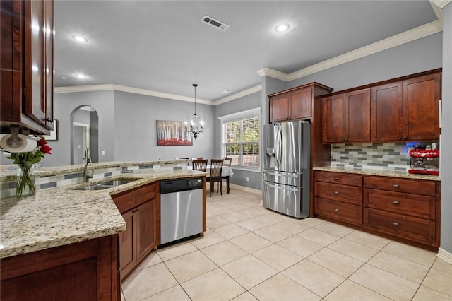 kitchen with appliances with stainless steel finishes, a sink, arched walkways, tasteful backsplash, and a peninsula