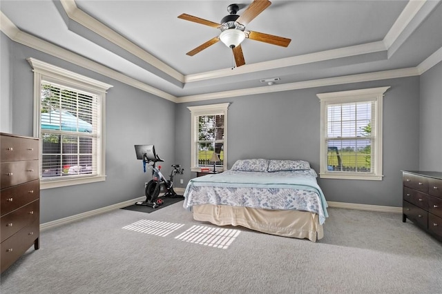 carpeted bedroom featuring a tray ceiling, multiple windows, ornamental molding, and baseboards