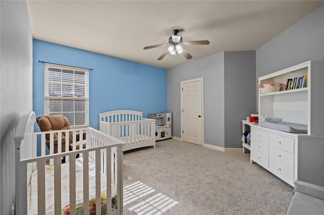 bedroom with carpet floors, baseboards, a ceiling fan, and a nursery area