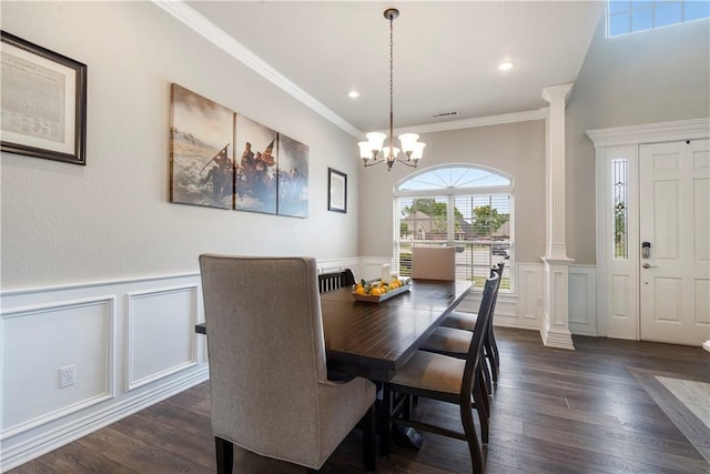 dining space with decorative columns, a decorative wall, dark wood-style floors, a chandelier, and crown molding