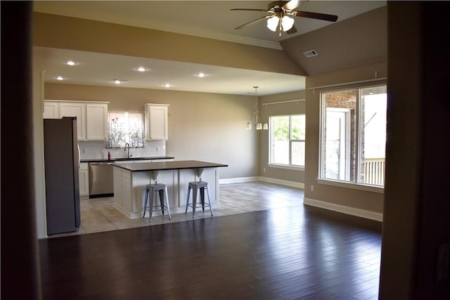 2402 N Brook Ln, Siloam Springs, AR 72761 - kitchen featuring stainless steel appliances, dark countertops, ceiling fan, a kitchen breakfast bar, and a center island