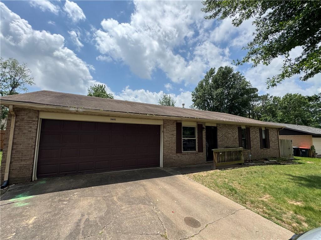 ranch-style house featuring brick siding, an attached garage, driveway, and a front yard