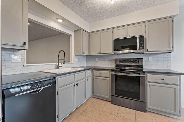 16 Eleanor Ln, Bella Vista, AR 72714 - kitchen featuring appliances with stainless steel finishes, a sink, dark countertops, light tile patterned floors, and gray cabinetry