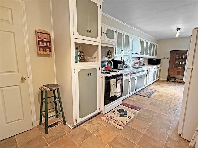 1711 W Cline Rd, Clarksville, AR 72830 - kitchen featuring range with gas stovetop, a sink, freestanding refrigerator, stainless steel microwave, and crown molding