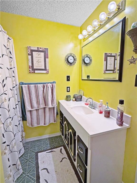 1711 W Cline Rd, Clarksville, AR 72830 - bathroom with vanity, a textured ceiling, baseboards, and tile patterned floors