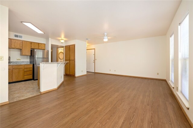 413 Columbia Pl, Lowell, AR 72745 - kitchen featuring freestanding refrigerator, light wood-style flooring, light countertops, brown cabinets, and open floor plan