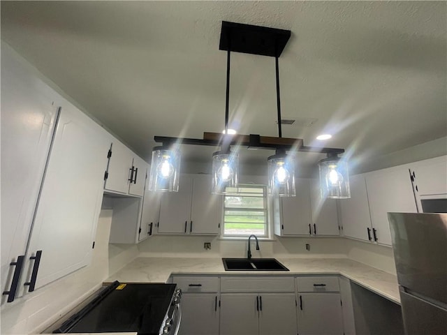 401 Walnut St, Clarksville, AR 72830 - kitchen with black stove, white cabinets, and freestanding refrigerator