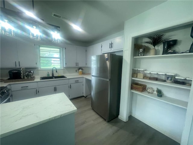 401 Walnut St, Clarksville, AR 72830 - kitchen with freestanding refrigerator, light wood-style floors, white cabinetry, and range with gas cooktop