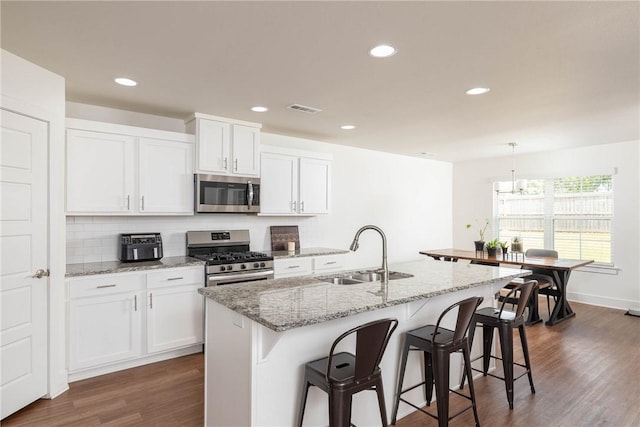 2758 Suncrest Ave, Springdale, AR 72764 - kitchen with stainless steel appliances, a sink, white cabinetry, dark wood-style flooring, and a breakfast bar area