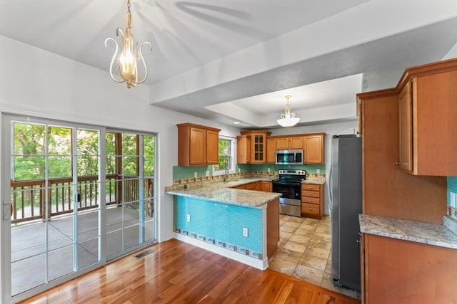 1878 Morning Side Falls Blvd, Blue Eye, MO 65611 - kitchen with appliances with stainless steel finishes, brown cabinets, a chandelier, a peninsula, and a tray ceiling
