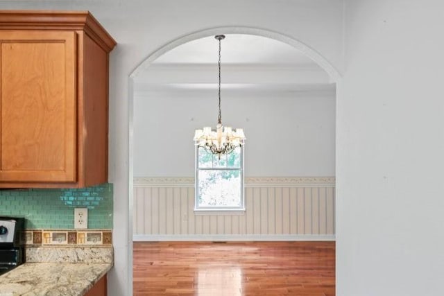 1878 Morning Side Falls Blvd, Blue Eye, MO 65611 - unfurnished dining area with light wood-type flooring, arched walkways, a chandelier, and a wainscoted wall