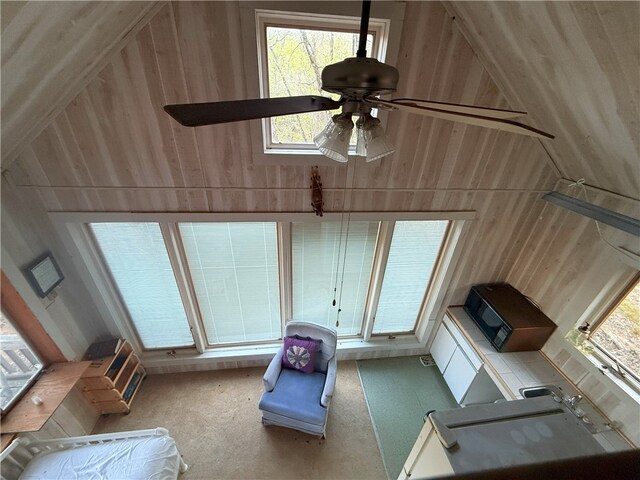 1088 Little Red River Rd, Leslie, AR 72645 - unfurnished living room featuring wood walls, a ceiling fan, lofted ceiling, carpet flooring, and plenty of natural light