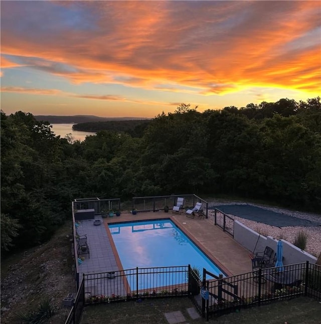 8141 Ward Ln, Rogers, AR 72756 - pool at dusk featuring a patio area and a forest view