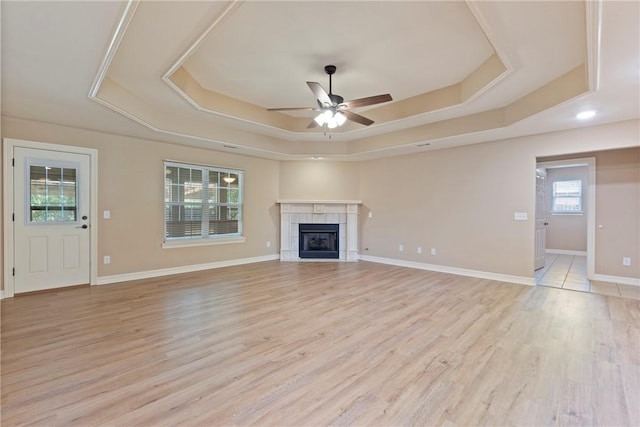 708 Carter Ct, Siloam Springs, AR 72761 - unfurnished living room featuring a raised ceiling, a ceiling fan, light wood-style flooring, a fireplace, and baseboards