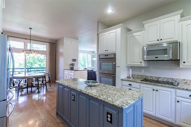 2507 NW Linebarger Ln, Bentonville, AR 72712 - kitchen with appliances with stainless steel finishes, white cabinets, a kitchen island, decorative backsplash, and light wood finished floors