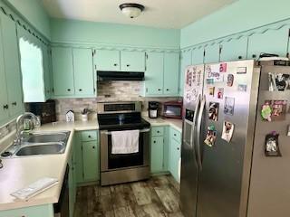 410 E Harvard St, Siloam Springs, AR 72761 - kitchen featuring appliances with stainless steel finishes, a sink, under cabinet range hood, light countertops, and decorative backsplash
