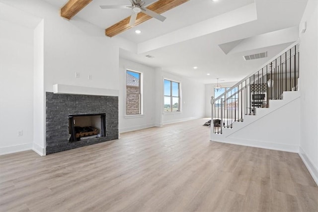 6601 SW Acacia St, Bentonville, AR 72713 - unfurnished living room featuring light wood finished floors, baseboards, stairway, a fireplace, and beamed ceiling