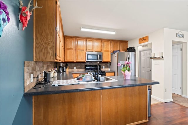 928 S Maple St, Siloam Springs, AR 72761 - kitchen featuring stainless steel appliances, a peninsula, decorative backsplash, dark wood finished floors, and dark countertops