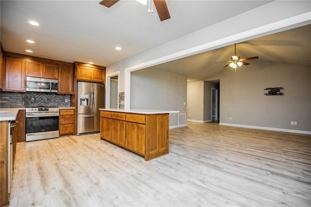 16 Stirling Ln, Bella Vista, AR 72715 - kitchen featuring appliances with stainless steel finishes, ceiling fan, brown cabinets, tasteful backsplash, and light wood-style floors