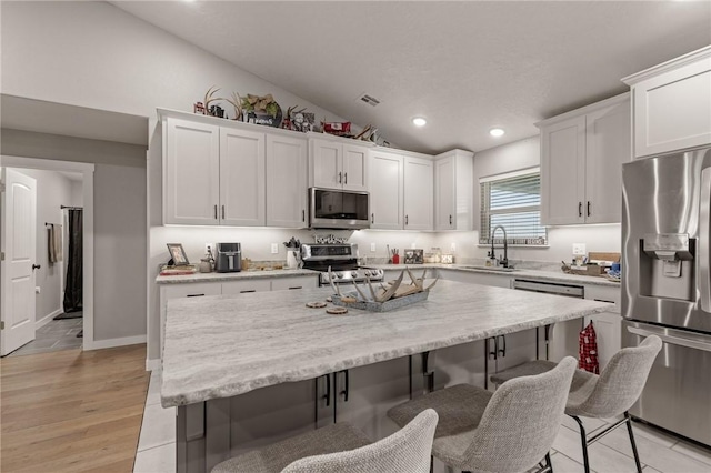 13865 State Highway 116, Colcord, OK 74338 - kitchen featuring appliances with stainless steel finishes, a sink, a breakfast bar area, white cabinets, and vaulted ceiling