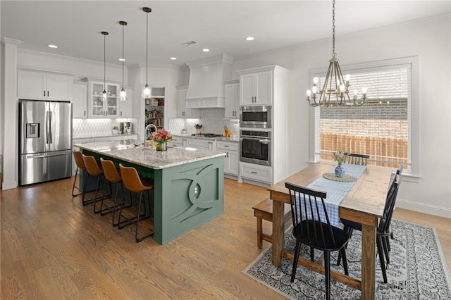 120 Bequette Ln, Centerton, AR 72719 - kitchen featuring stainless steel appliances, premium range hood, white cabinetry, a chandelier, and a kitchen bar