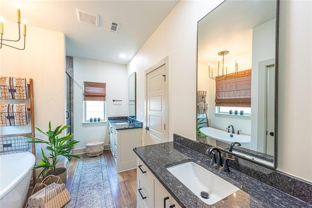 852 Round Top St, Prairie Grove, AR 72753 - bathroom featuring a chandelier, wood finished floors, a stall shower, a freestanding bath, and two vanities
