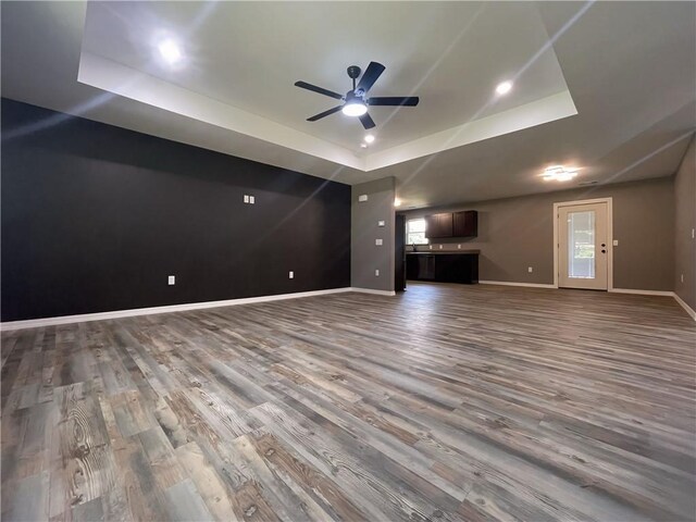 2103 Highland Ct, Dardanelle, AR 72834 - unfurnished living room featuring a tray ceiling, wood finished floors, baseboards, and ceiling fan