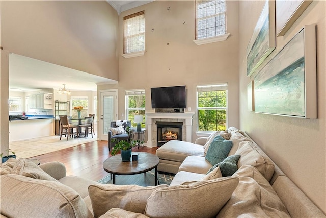 4730 Woodside Ln, Springdale, AR 72762 - living room with wood finished floors, a chandelier, a tiled fireplace, plenty of natural light, and a high ceiling