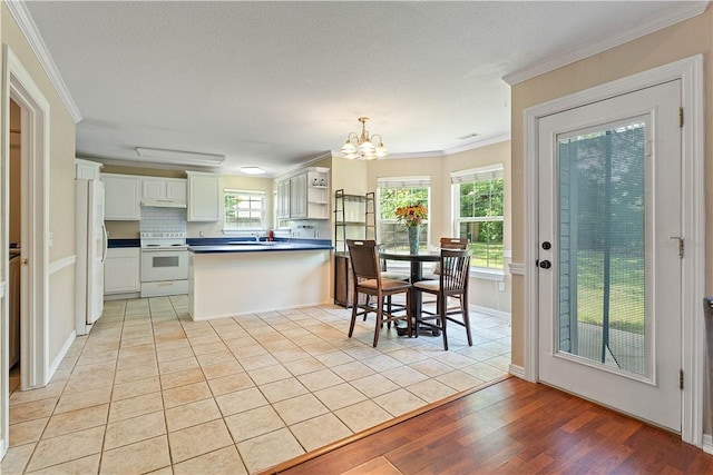 4730 Woodside Ln, Springdale, AR 72762 - kitchen featuring white appliances, a peninsula, ornamental molding, dark countertops, and a chandelier