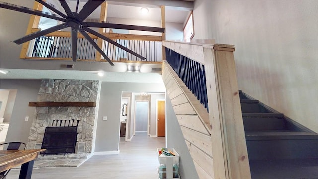 104 NE Deer Ridge Rd, Gravette, AR 72736 - unfurnished living room with a fireplace, ceiling fan, wood finished floors, a towering ceiling, and stairway