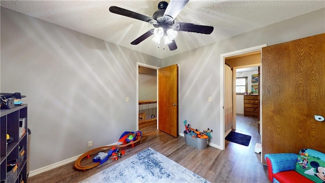 104 NE Deer Ridge Rd, Gravette, AR 72736 - playroom featuring wood finished floors, ceiling fan, baseboards, and a textured ceiling